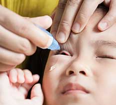 Small kid taking eye drops for controlling progressive myopia
